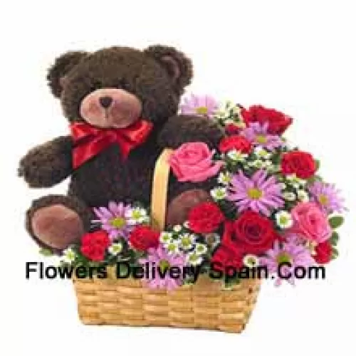 Ein schöner Korb aus roten und rosa Rosen, roten Nelken und anderen verschiedenen lila Blumen zusammen mit einem niedlichen 14 Zoll großen Teddybär